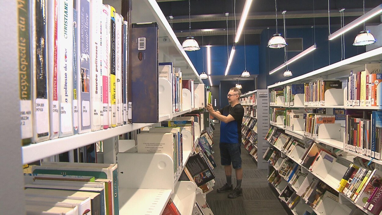 Un homme entre les rangées de livres