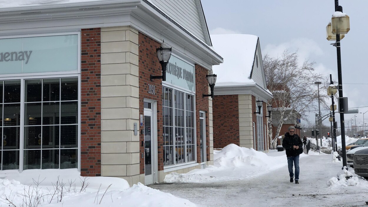 Un homme marche devant une bibliothèque.