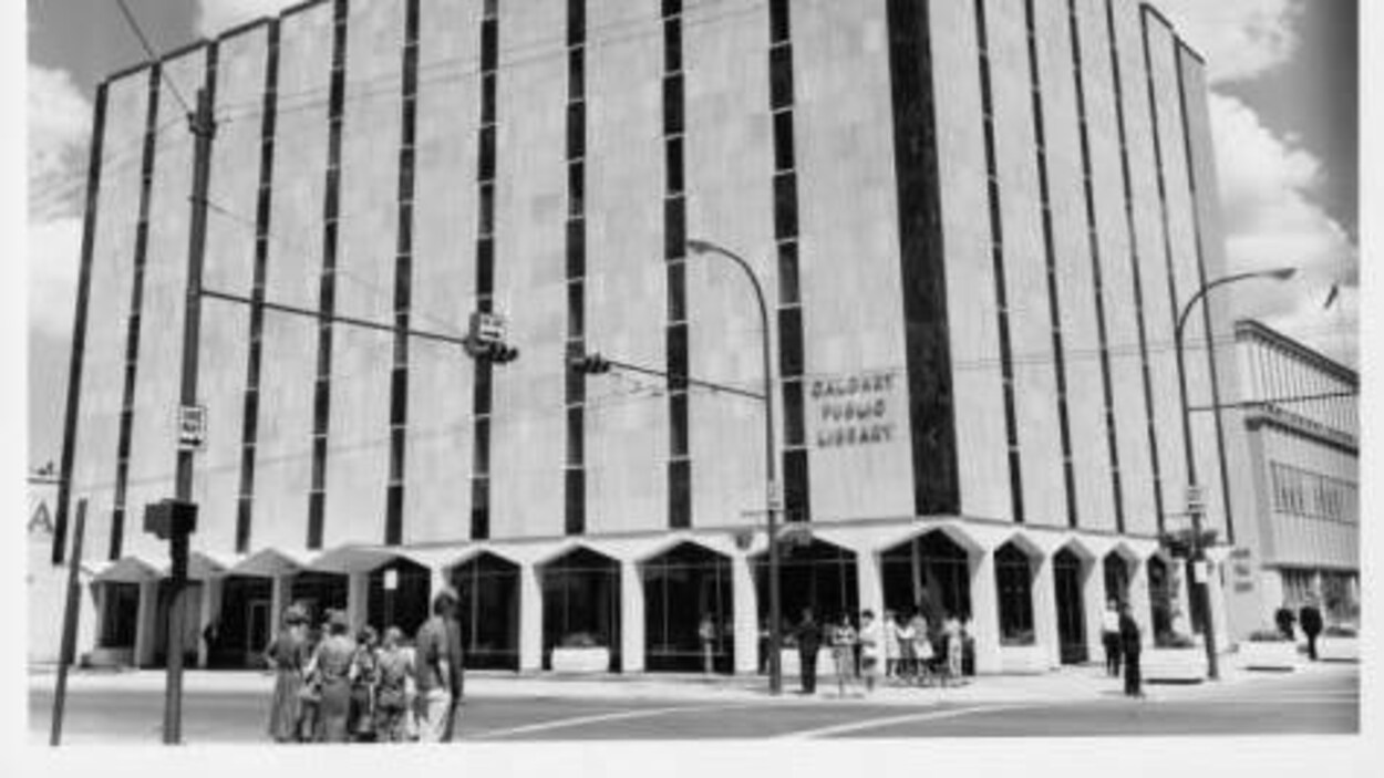 Une vieille photo de la bibliothèque, il y a des gens autour de l'entrée.