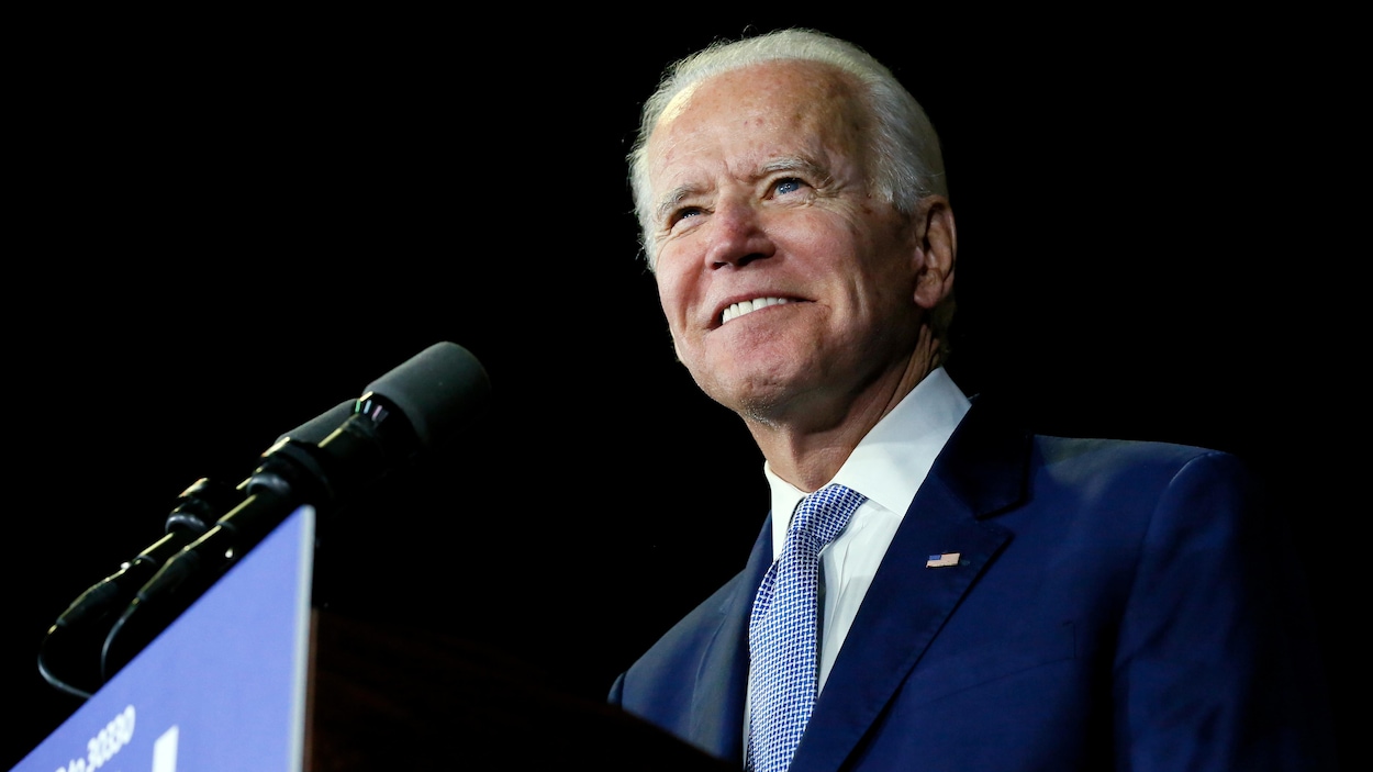 Joe Biden, souriant, devant un micro
