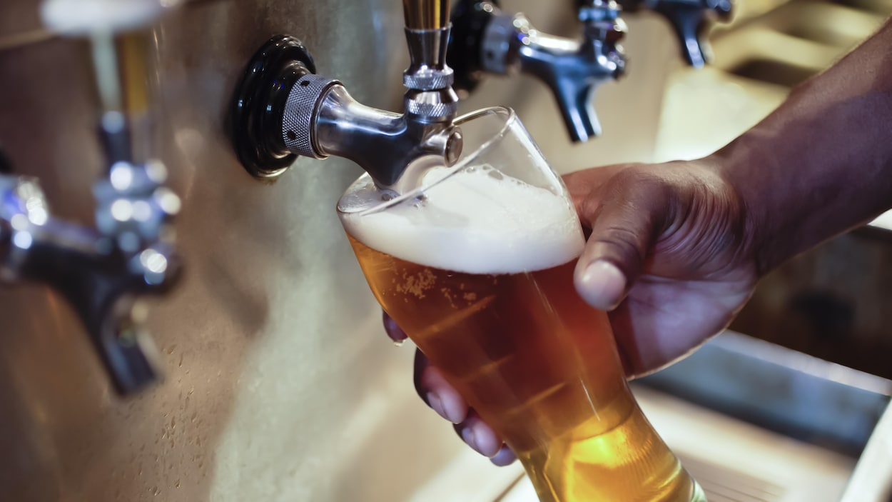 Un homme remplit un verre de bière en fût.