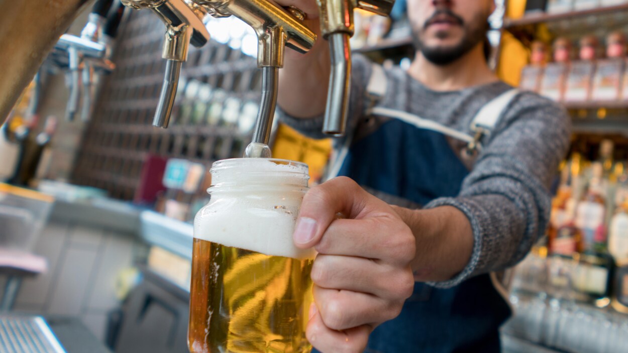 Un homme fait couler de la bière dans un pot masson