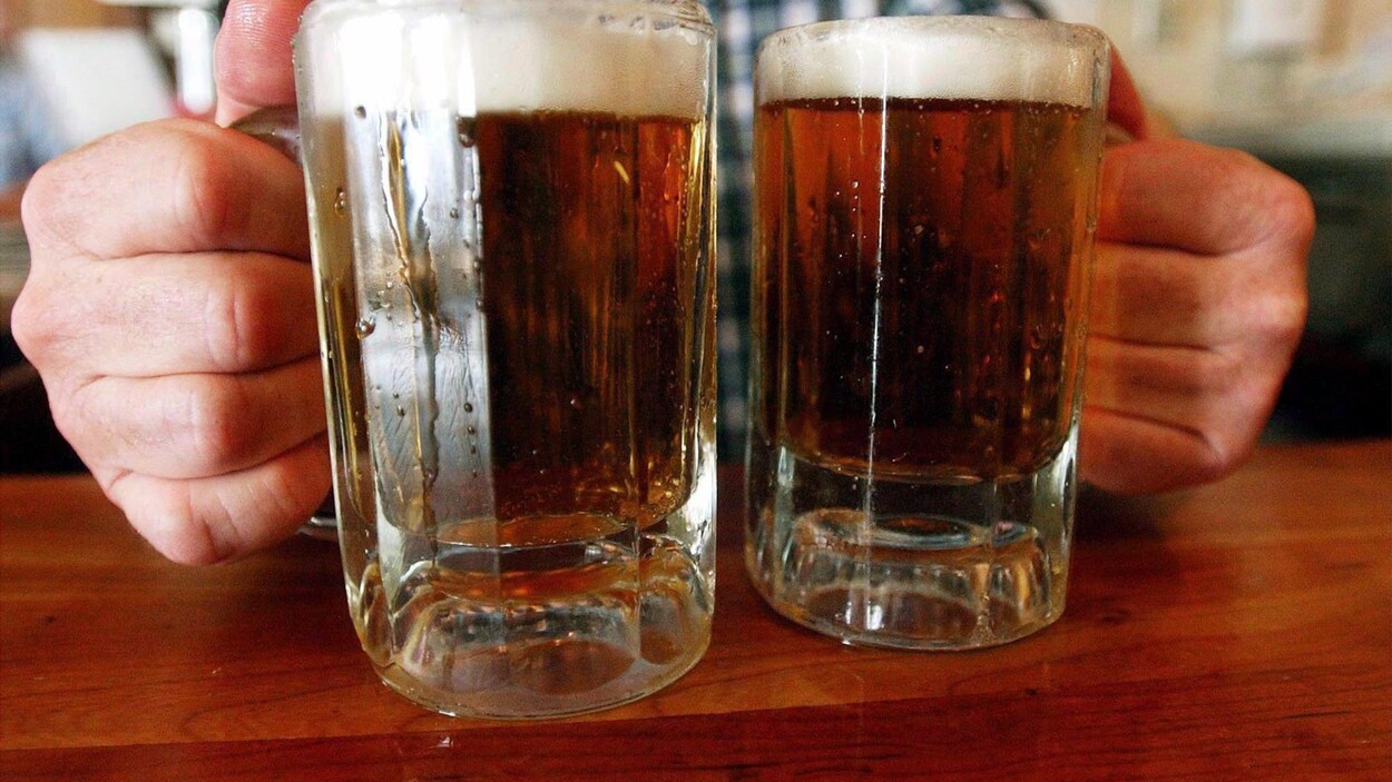 Un homme tient deux pintes de bière.