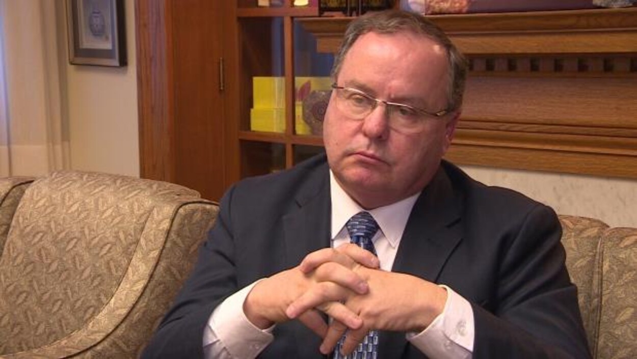 Bill Boyd est assis, les main croisées. Bill Boyd est assis, les main croisées.