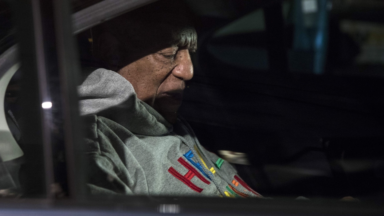 Le comédien croqué par les photographes dans une voiture avec de la lumière sur la moitié de son visage.