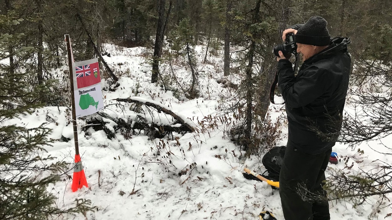 Un homme prend une photo d'un marqueur en forêt.