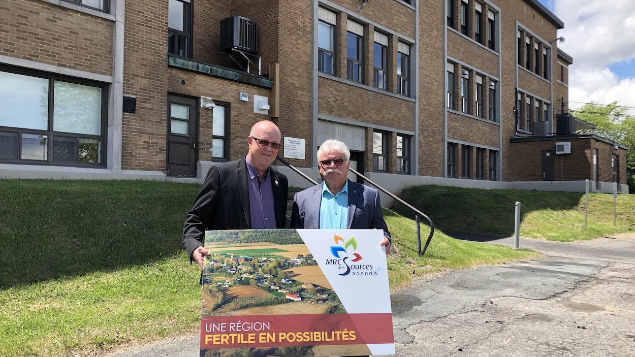 Deux hommes posent en tenant une affiche où il est écrit «une région fertile en possibilités»