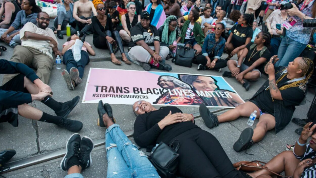 Des militants sont allongés sur le sol autour d'une grosse pancarte sur laquelle on peut lire : les vies des Noirs trans comptent