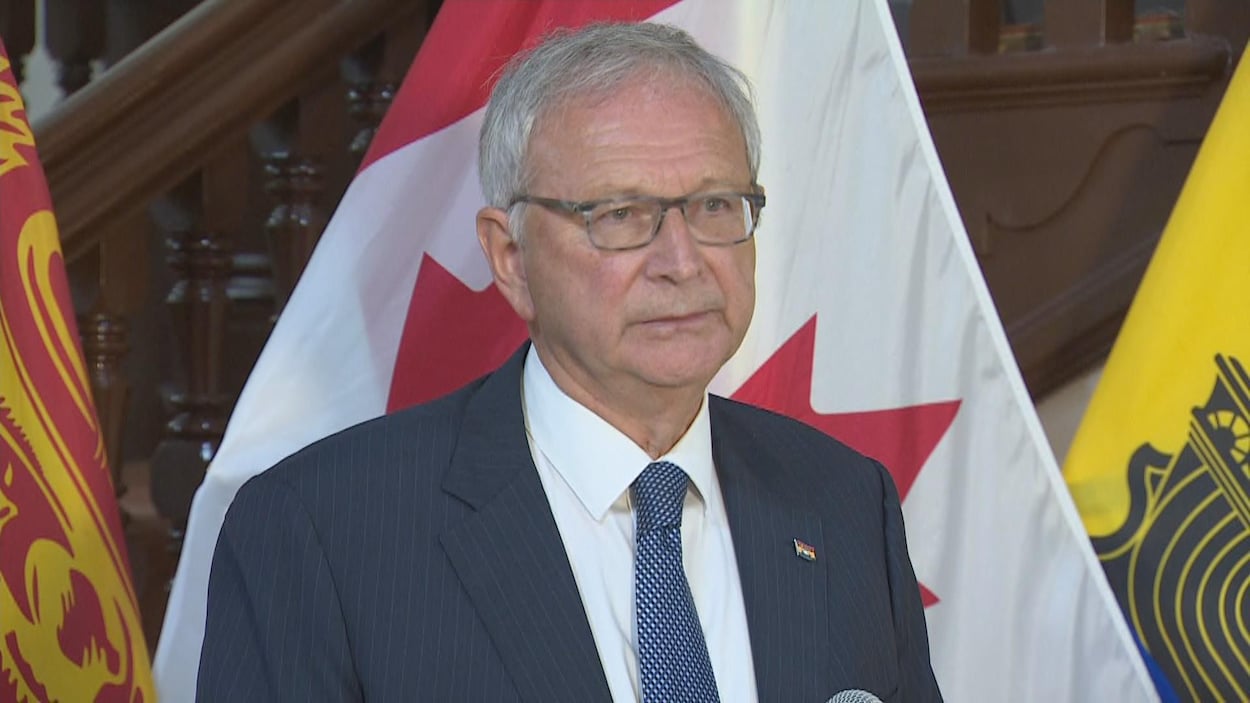 Blaine Higgs en conférence de presse devant des drapeaux du Canada et du Nouveau-Brunswick.