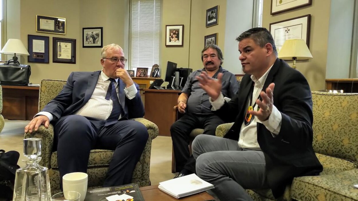 Trois hommes assis dans un bureau.