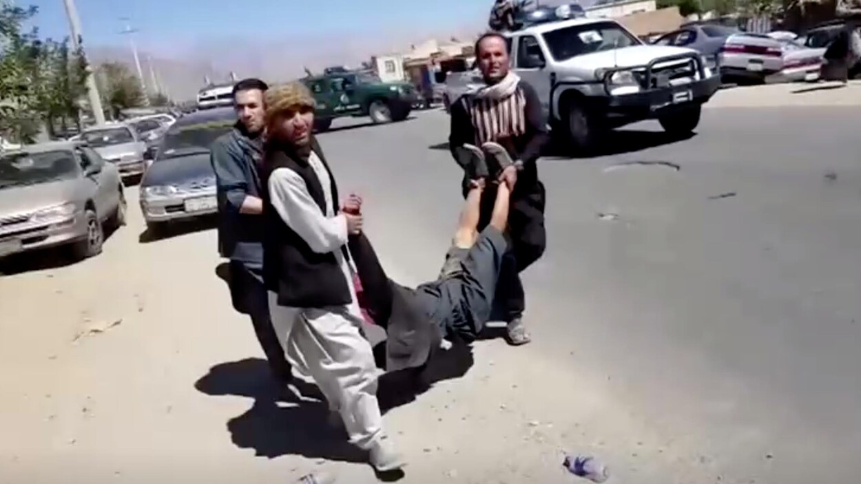 Des hommes transportent un corps dans la rue.