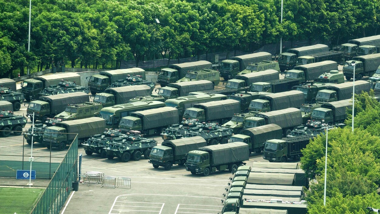 Des camions et des véhicules blindés de transport de troupes près du stade de Shenzhen Bay.