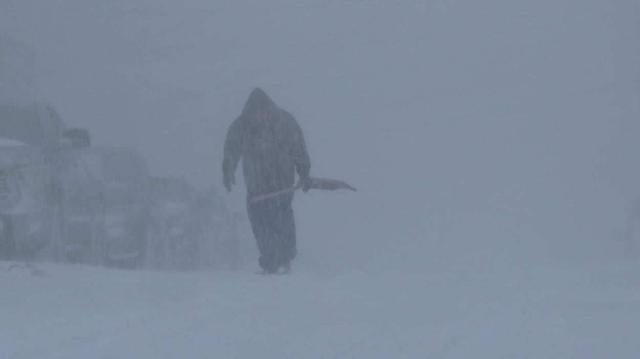 Un homme avec une pelle dans un blizzard.