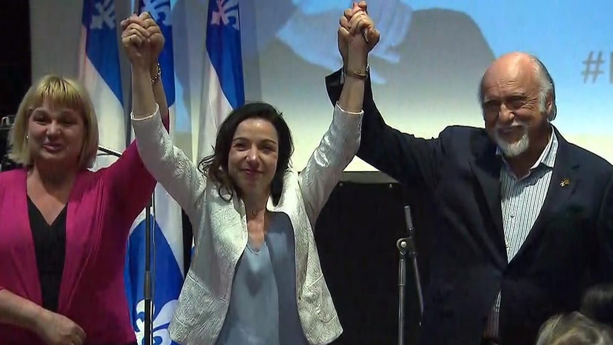 Les deux bras levés, Martine Ouellet tient la main de Sophie Stanké d'un côté et celle de Gilbert Paquette, de l'autre. Les deux bras levés, Martine Ouellet tient la main de Sophie Stanké d'un côté et celle de Gilbert Paquette, de l'autre.