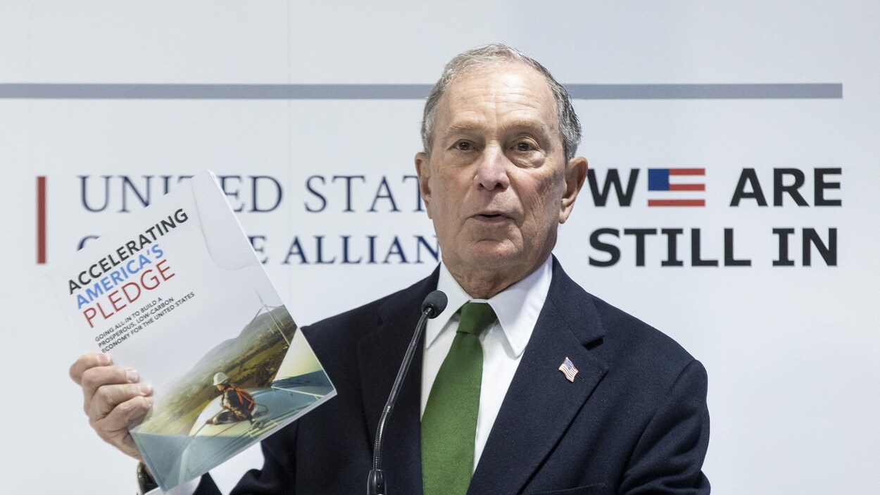 Michael Bloomberg s'adresse à son auditoire avec un document à la main.