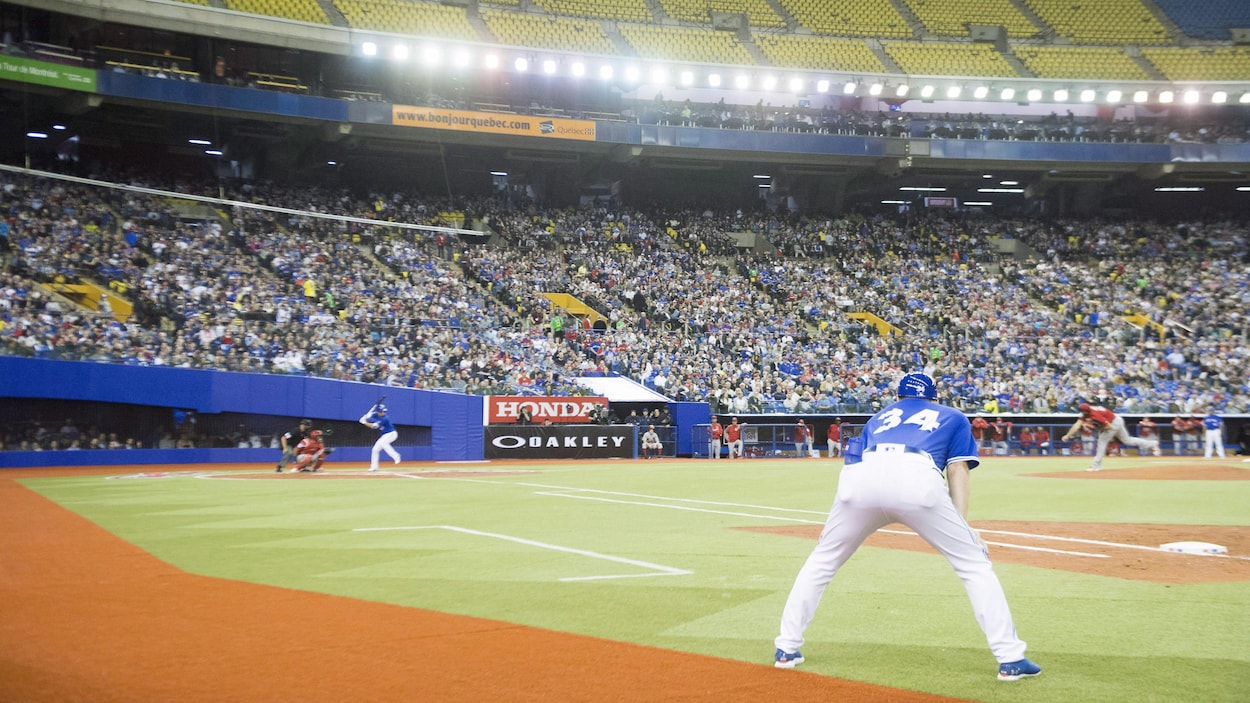 L'instructeur du premier but des Blue Jays regarde attentivement le lanceur et le frappeur s'élancer lors du match du 26 mars au stade olympique. L'instructeur du premier but des Blue Jays regarde attentivement le lanceur et le frappeur s'élancer lors du match du 26 mars au stade olympique.