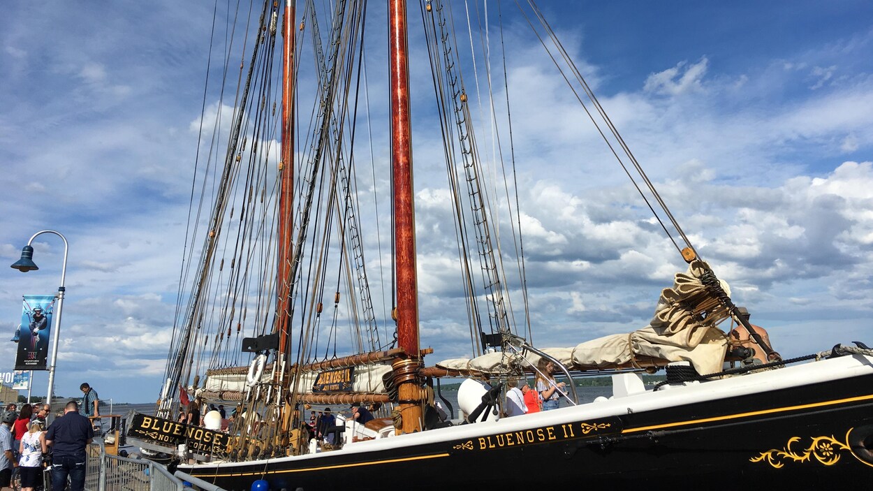 La réplique du légendaire Bluenose, accosté, avec des visiteurs à bord.