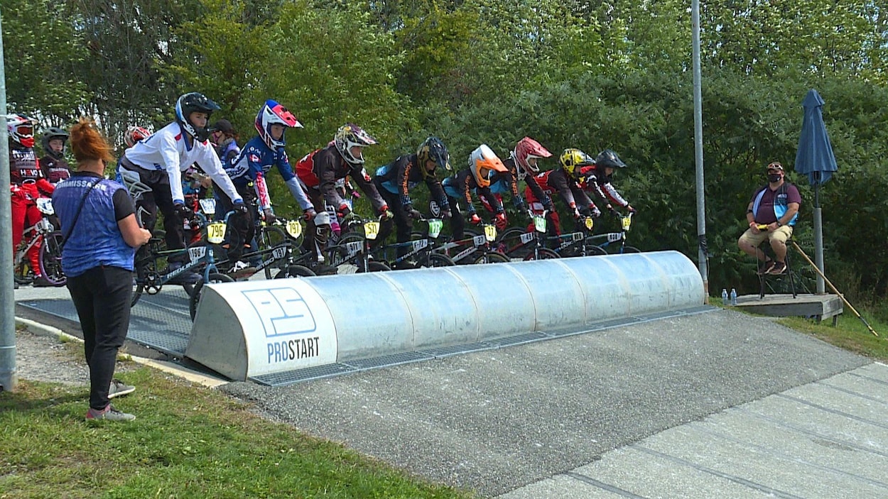 Des pilotes de BMX attendent derrière le portillon de départ.