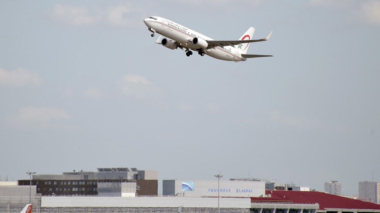 Un avion est dans les airs, au-dessus d'édifices.