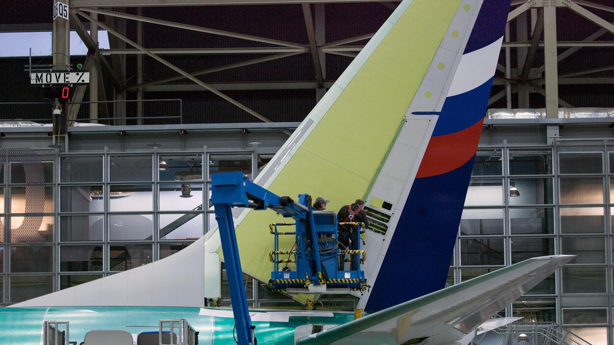 Des employés travaillent sur la queue de l'avion.