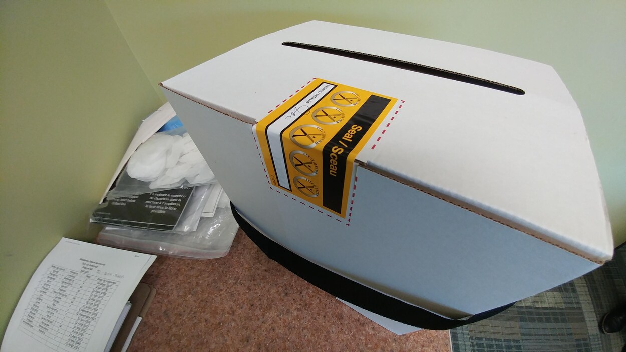 Une boîte de scrutin, encore scellé, repose sur une table.