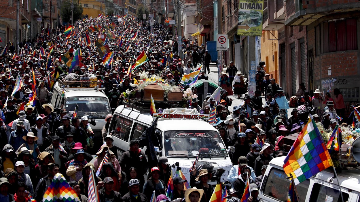 Une foule dans la rue avec des drapeaux autochtones.