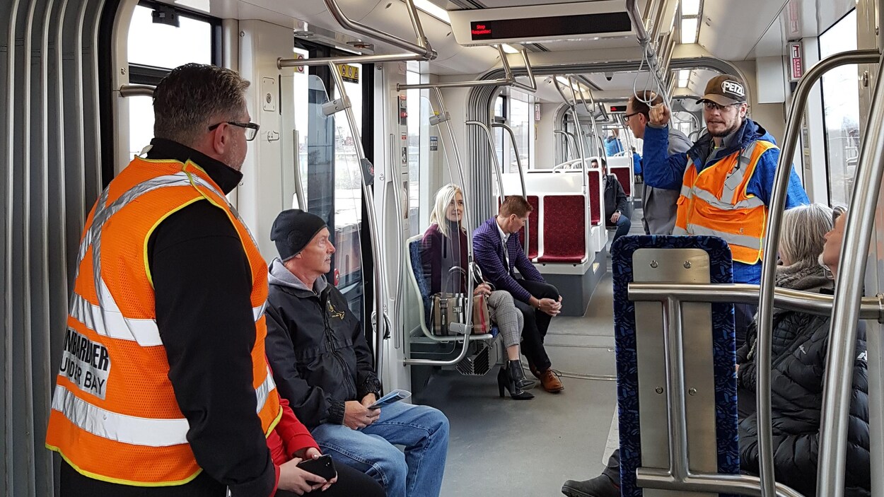 Des gens assis et debout dans un wagon de métro.