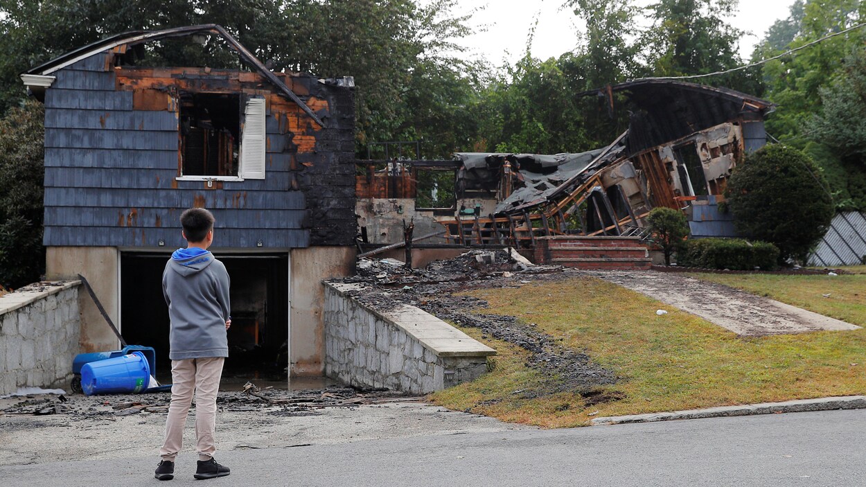 Un jeune garçon regarde une maison détruite par une explosion Un jeune garçon regarde une maison détruite par une explosion