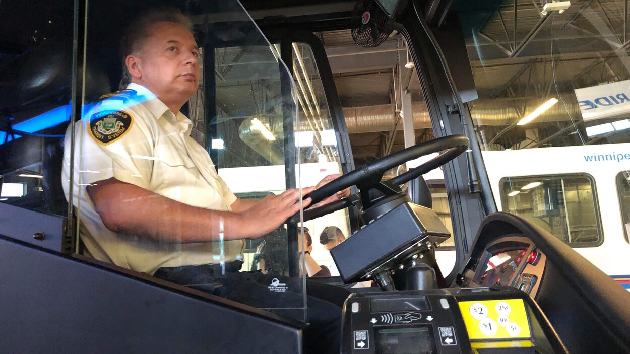 Un chauffeur d'autobus derrière un bouclier en plastique.