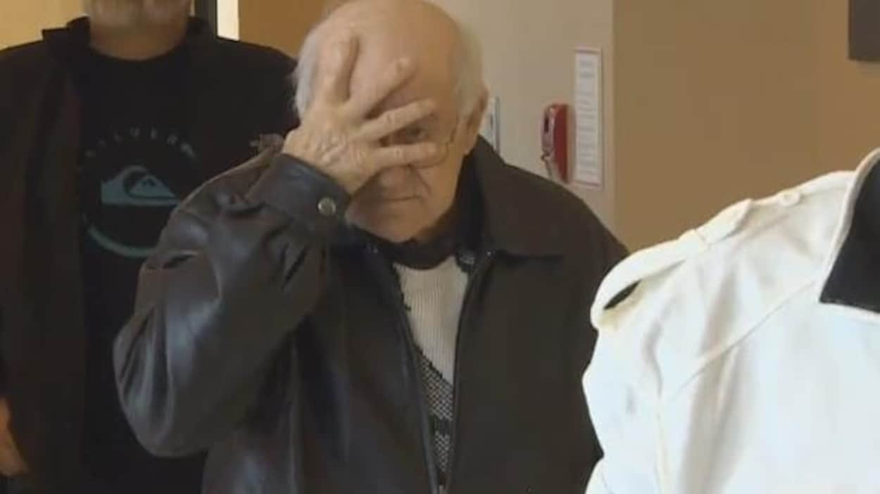 Delmore Boudreau se masque le visage d'une main en marchant dans le palais de justice