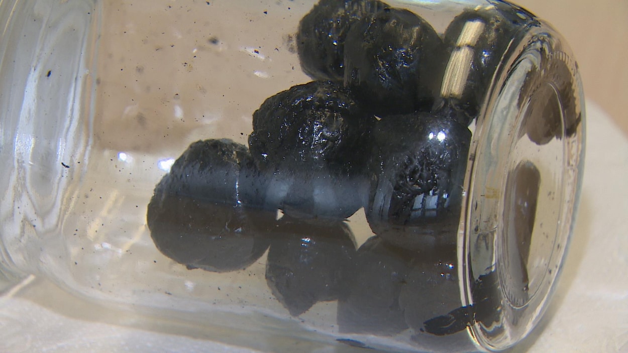 Une douzaine de billes noire dans un bocal de verre posé à l'horizontale Une douzaine de billes noire dans un bocal de verre posé à l'horizontale