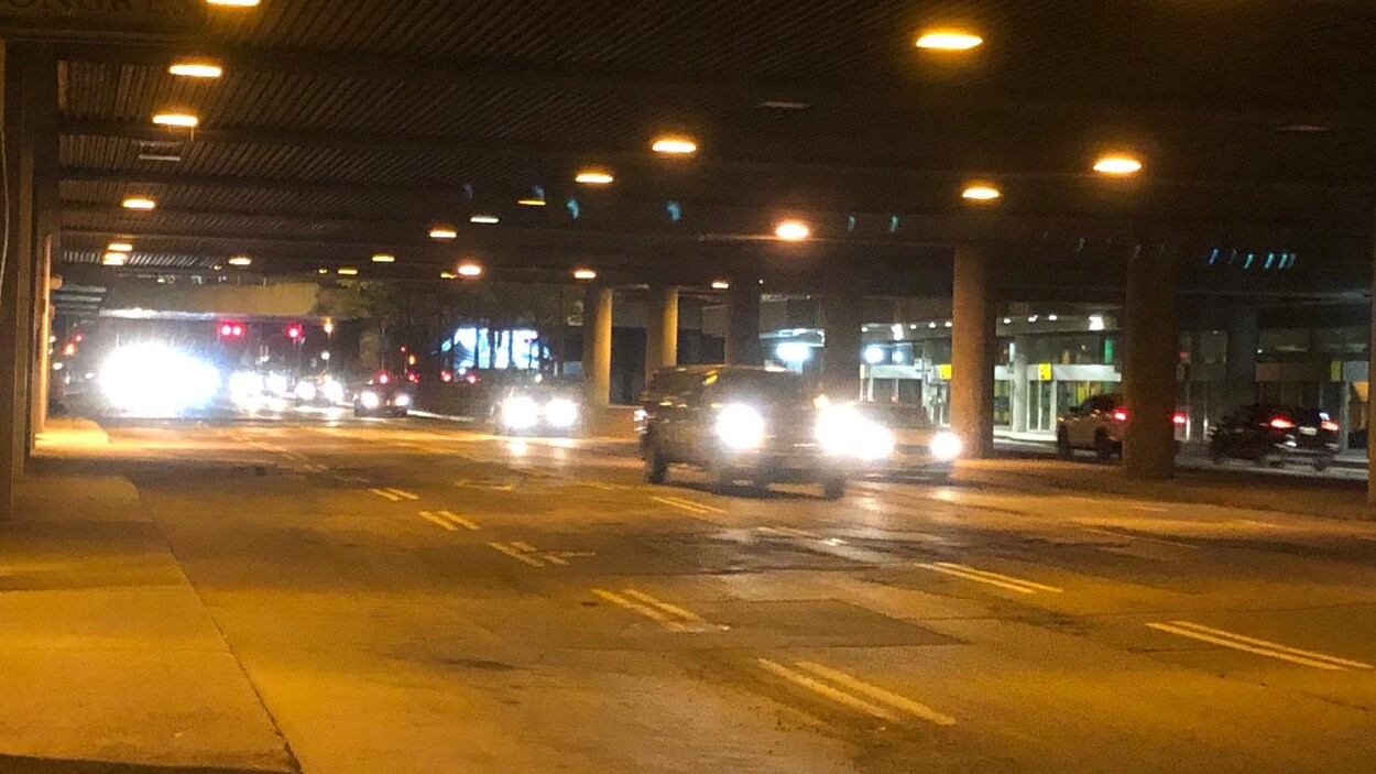 Des voitures sous la poutre du boulevard Maisonneuve, en soirée.
