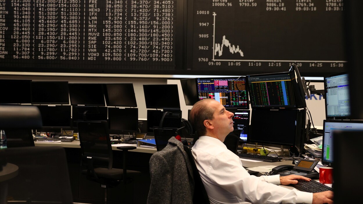 Un courtier à la Bourse de Francfort devant un tableau affichant l'indice Dax.