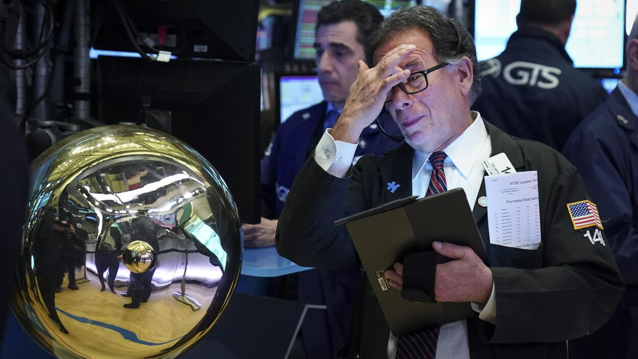 Un courtier ayant une tablette en main se gratte le front.