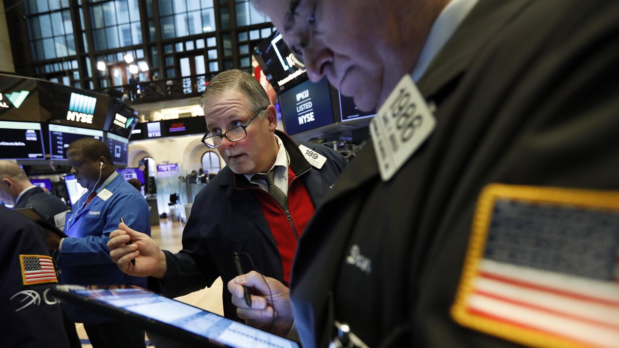 Des employés de la Bourse à New York s'affairent, la mine soucieuse.