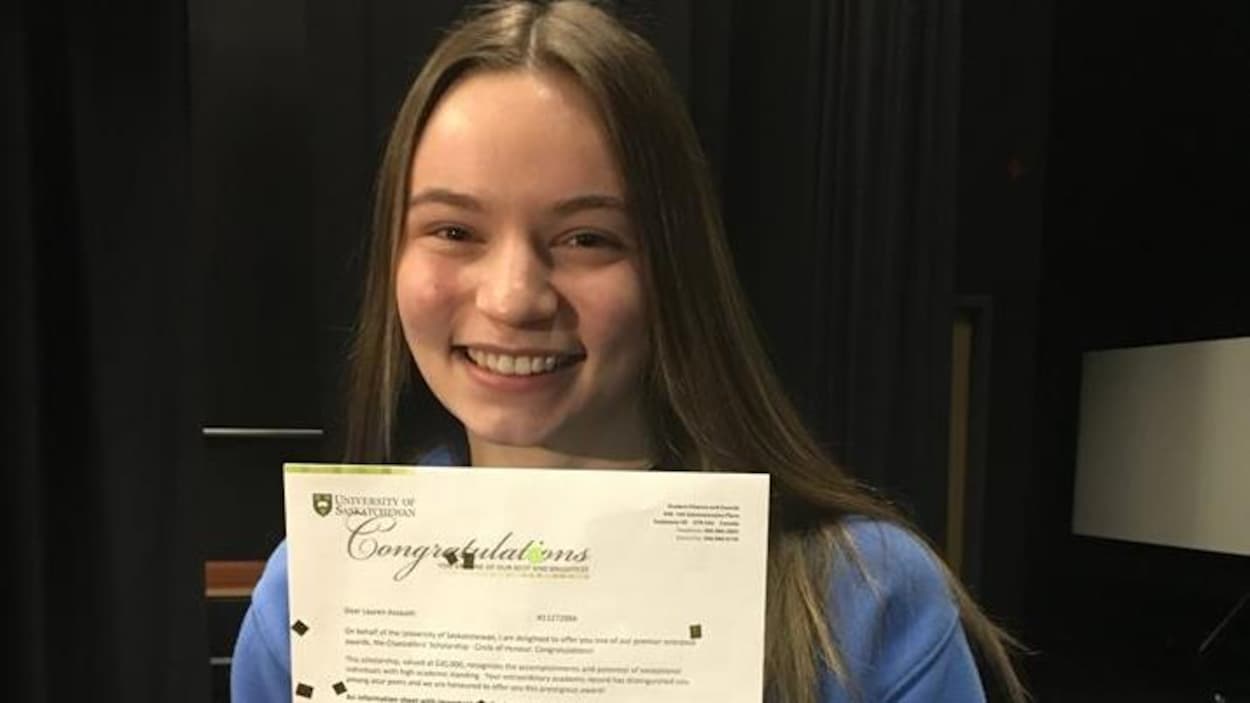 Une jeune femme pose fièrement avec un document la félicitant.