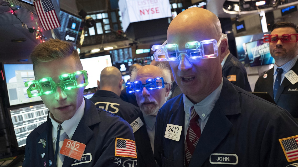 Quatre hommes portent des lunettes lumineuses affichant « 2020 » à la bourse de New York.