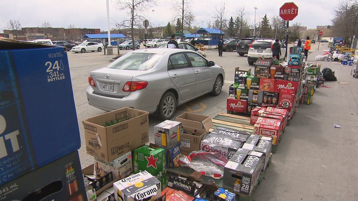 Une voiture attend devant une file de caisses de bière vide.