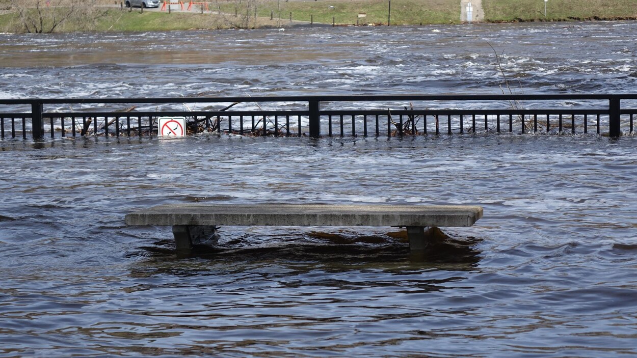 Photo d'un banc de parc submergé près d'une rivière