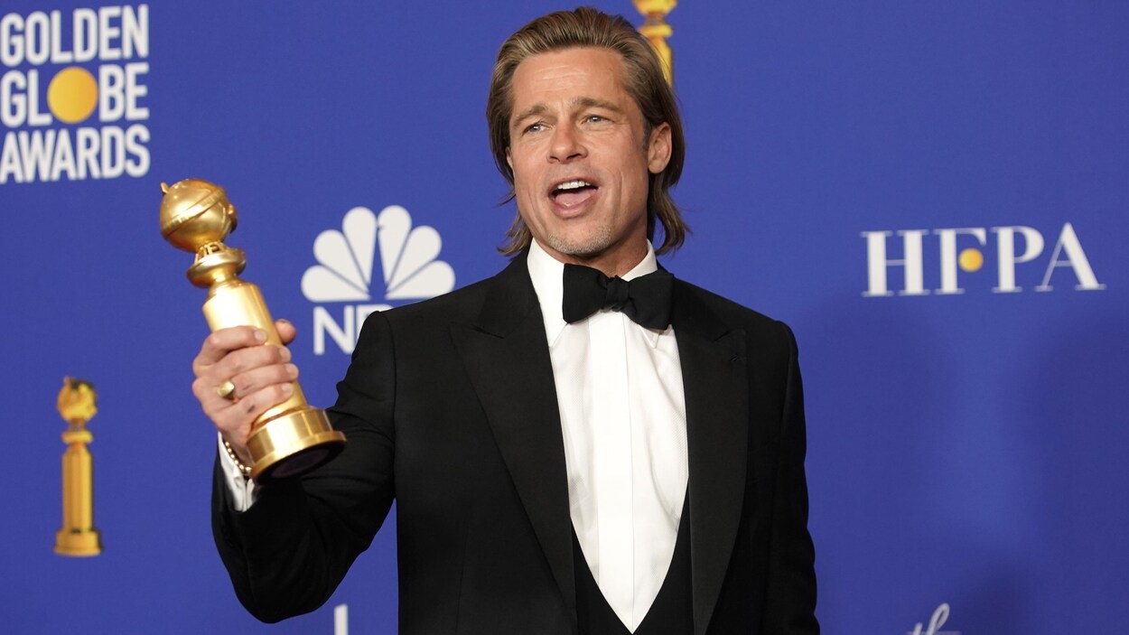 Brad Pitt tient le trophée qu'il vient de remporter.