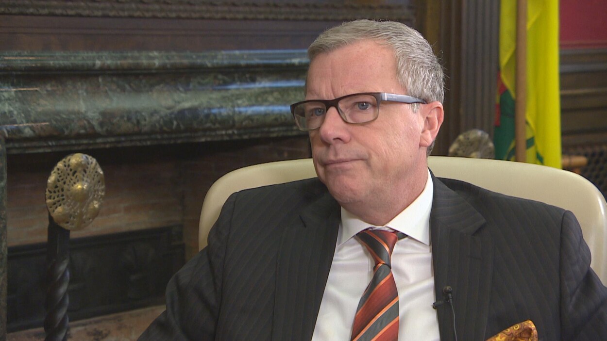 Plan moyen de Brad Wall assis dans un fauteuil au cours d'une entrevue.