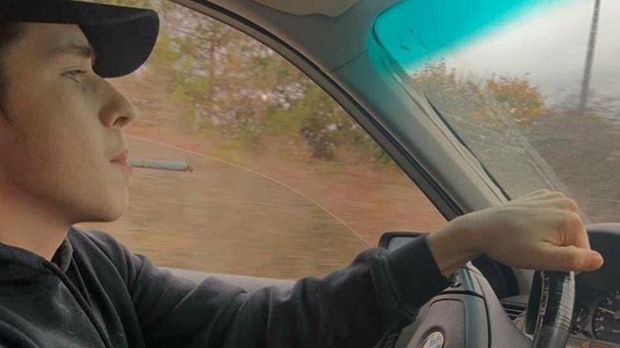 Un homme au volant fume une cigarette