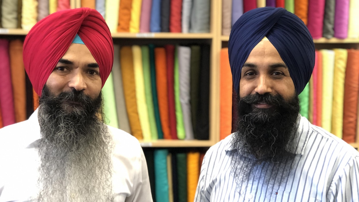 Deux vendeurs de turbans devant des tissus de toutes les couleurs.