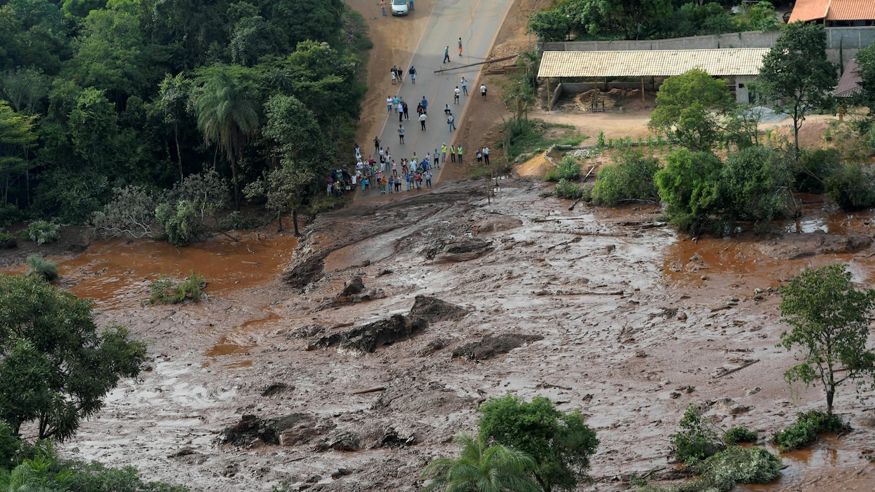 Vue aérienne du terrain inondé; des gens observent l'étendue des dégâts.