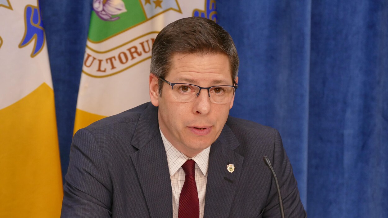 Le maire Brian Bowman est photographié en gros plan; on voit derrière lui une partie des drapeaux de la ville.