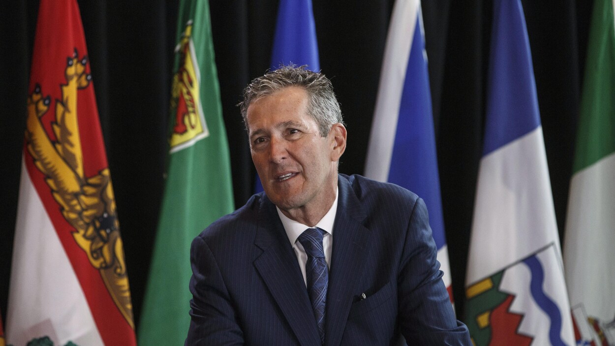 Le premier ministre du Manitoba, Brian Pallister, entouré de drapeaux. Le premier ministre du Manitoba, Brian Pallister, entouré de drapeaux.