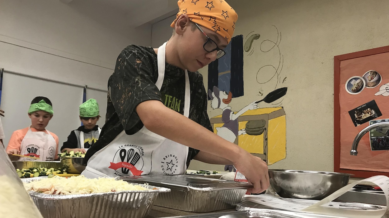 Un jeune homme ferme le couvercle d'une lasagne dans un plat en aluminium.