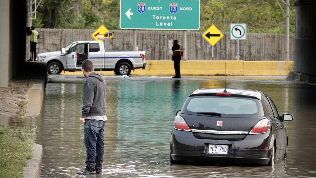 Un homme regarde l'accumulation d'eau avec au loin des employés municipaux.