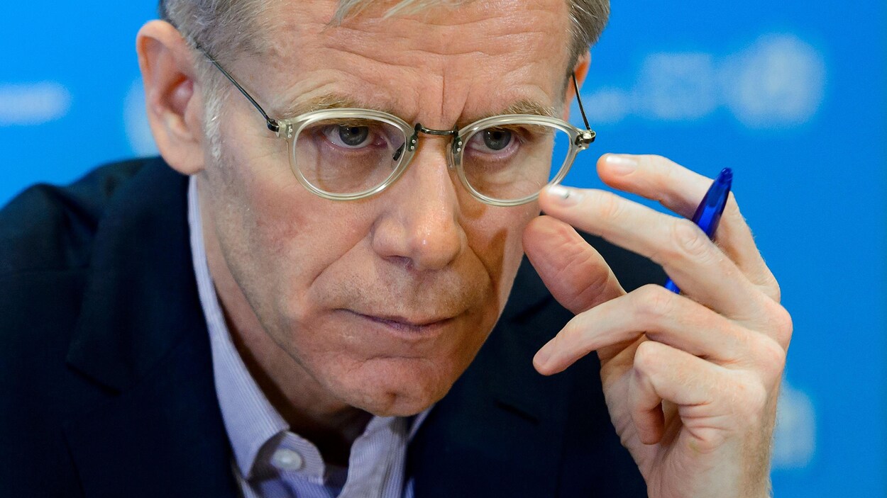 Gros plan de Bruce Aylward, qui ajuste ses lunettes.