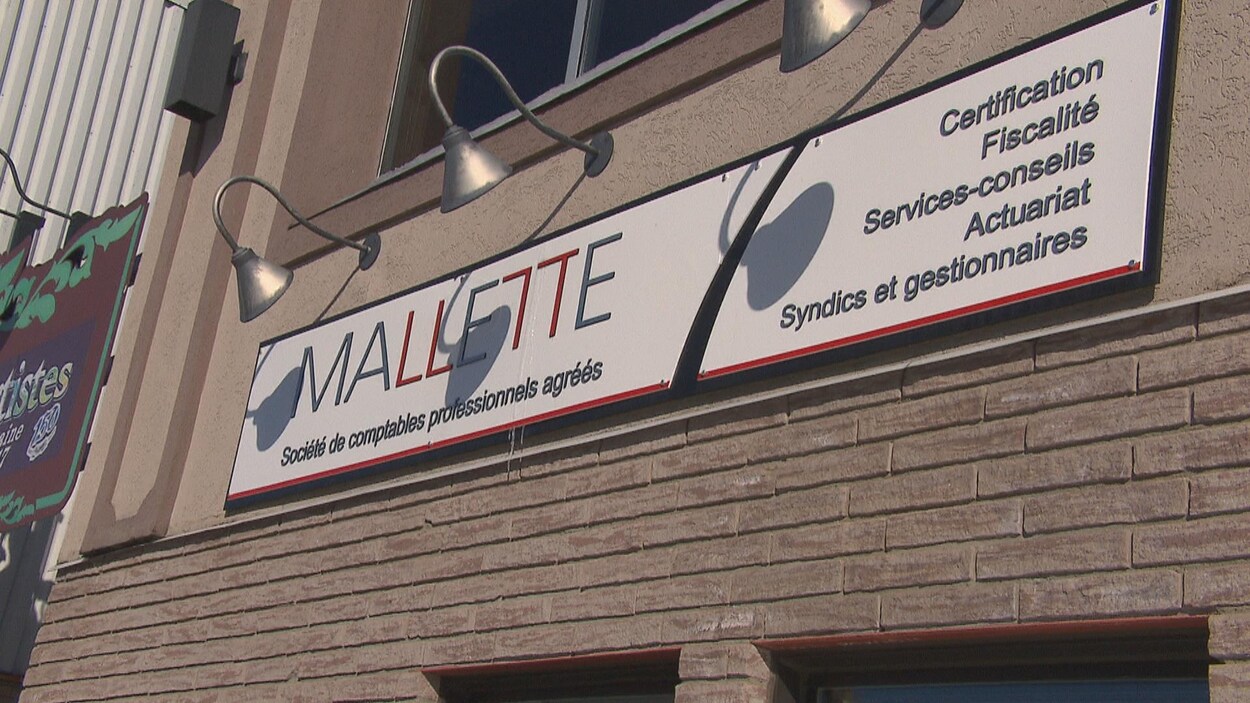 Une affiche indique le nom de l'entreprise sur un bâtiment de brique.